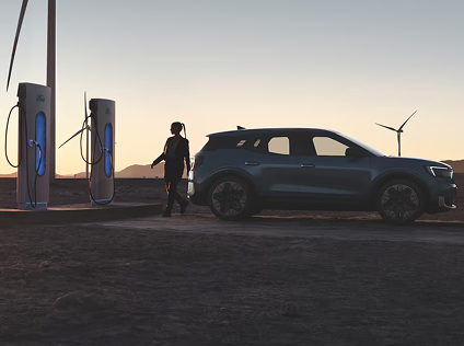 Ford vehicle next to a charging station in a desert setting.
